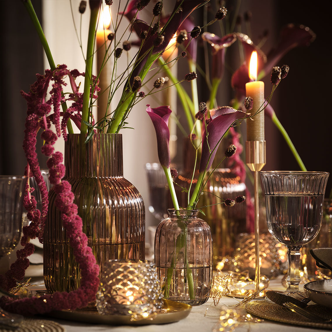 Vases with flowers and a candle stick with candle on set Christmas table 