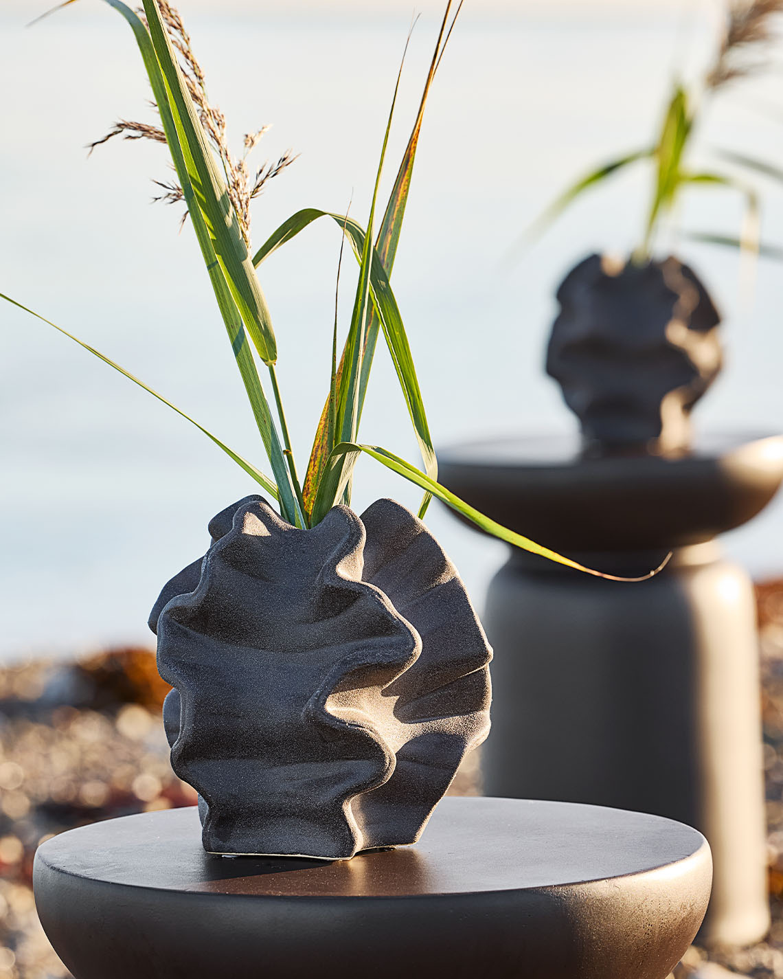 Organic shape vase on pedestal on a beach