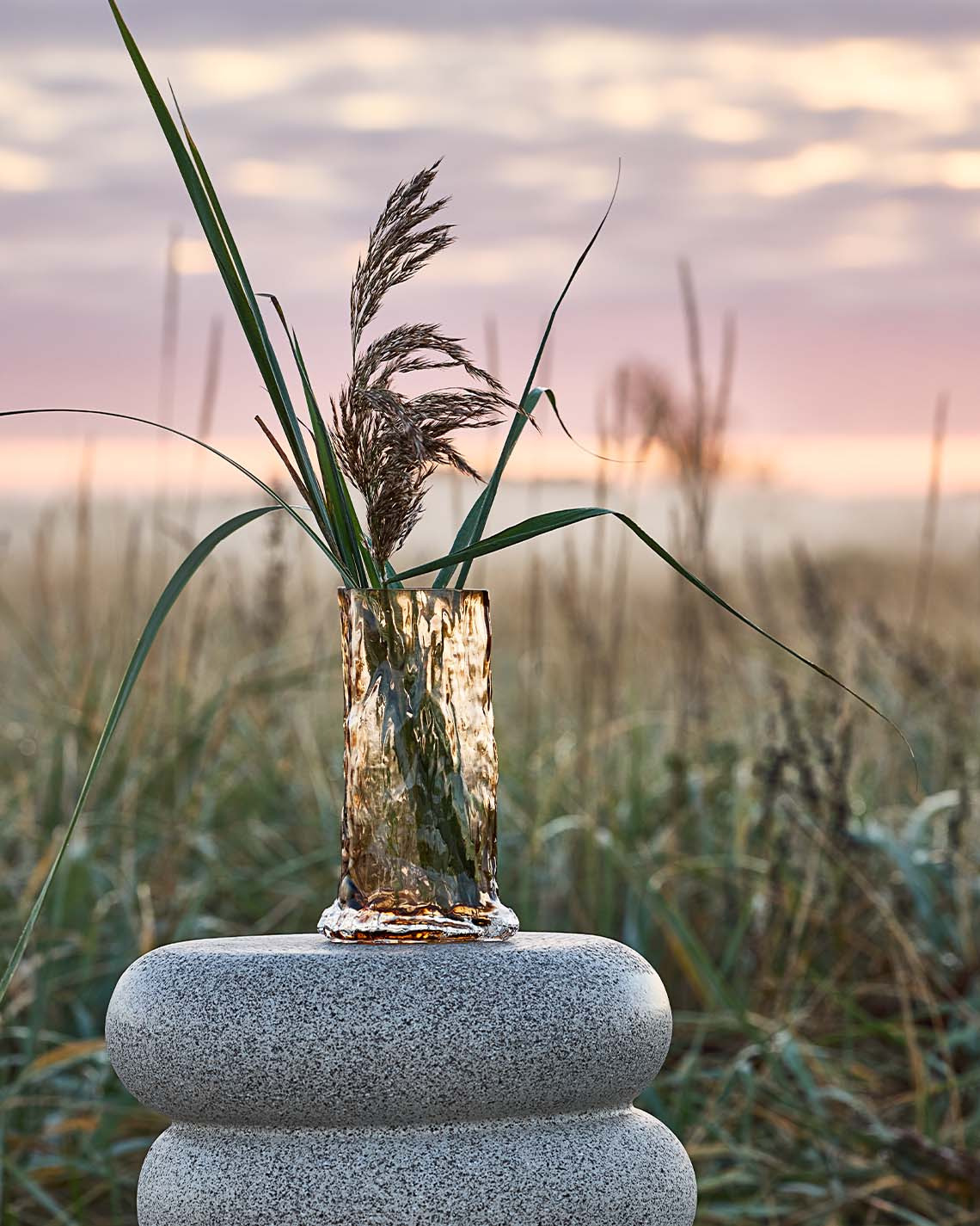 Tall vase on pedestal in the dunes near a beach