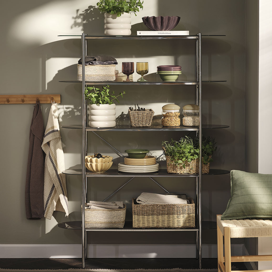 GREGERS cutlery, MALIK plates and bowls, ISAK glasses, FILIP basket, DAHL storage jars, BARLIND tea towels, POPPEL cushion covers, TISTEL tea towels, NOR bowls Colourful glasses, plates and bowls, baskets and storage jars on a shelving unit