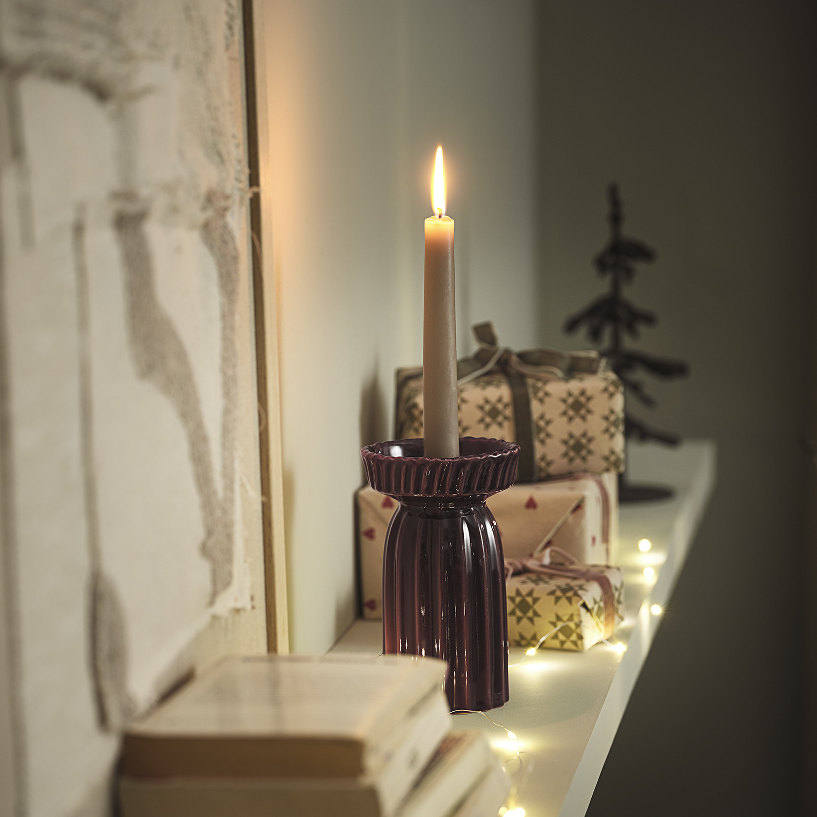 Candlestick with lit candle on a shelf