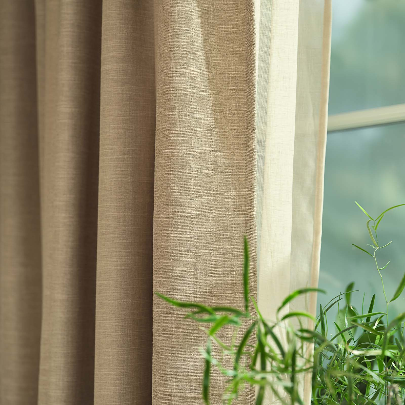 ASKROVA curtain in pale khaki Close-up of a khaki, sandy-coloured heavy curtain in front of window
