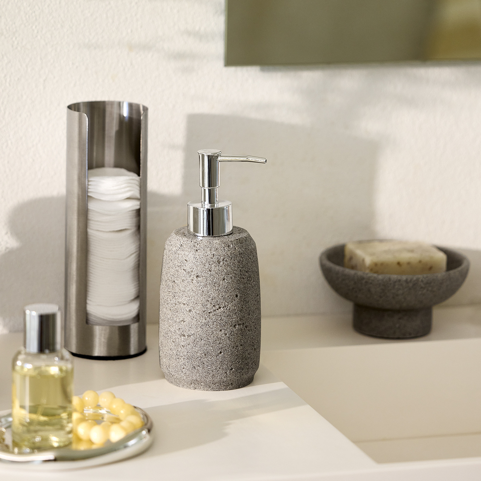 Soap dispenser, trinket dish and cotton pad holder by a bathroom sink 