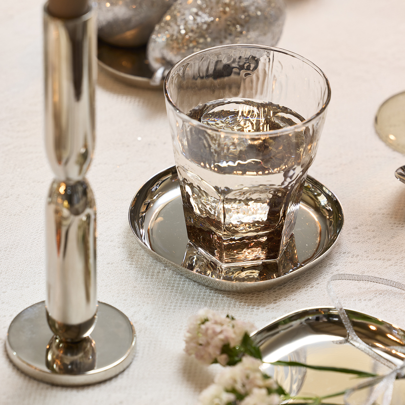 Drinking glass on silver coloured coaster on dinner table 