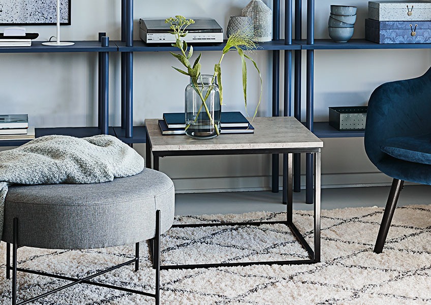 Living room with end table and pouffe in front of a bookcase 