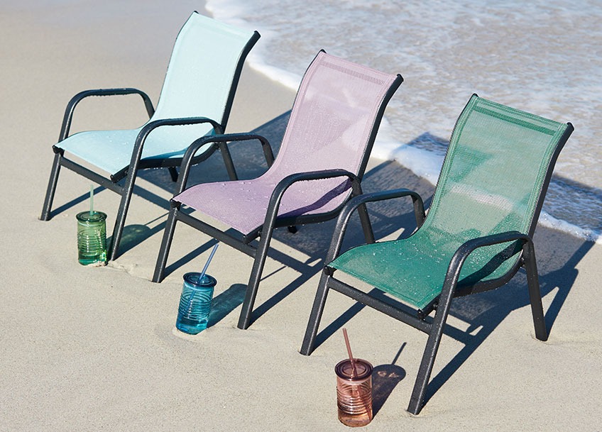 Children’s stacking chair on a beach with a drinking cup placed in front of each one