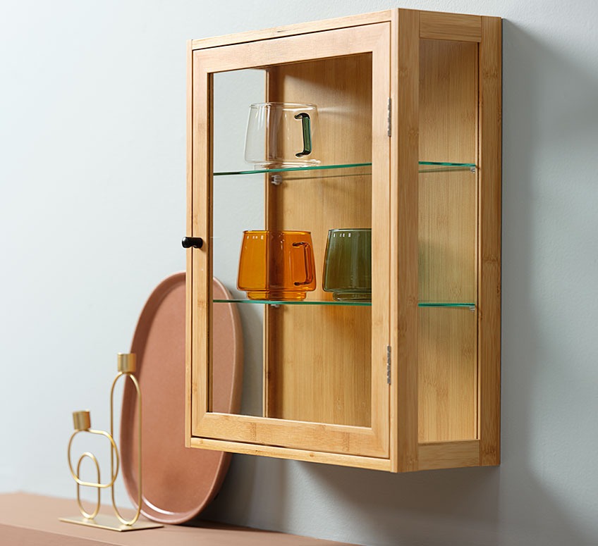 Small cabinet with hand-blown glass cups and candlestick and tray in the background