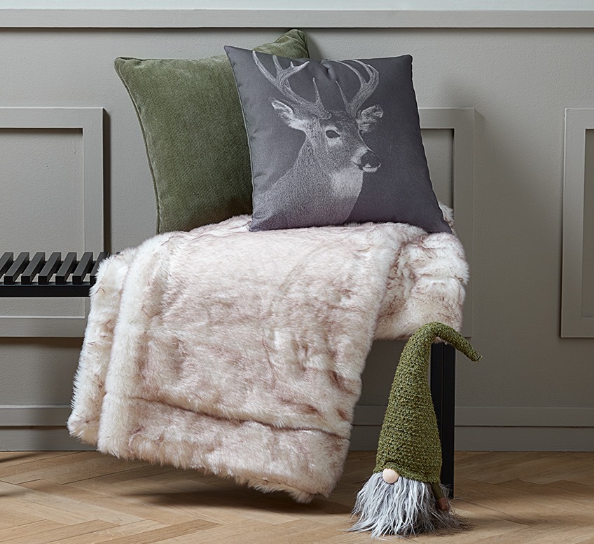 VIRUM bench with LIN and HORNFIOL cushions and SANDSTEN throw. On the floor ODIN elf. Bench with two Christmas cushions, a throw and on the floor an elf with a green hat
