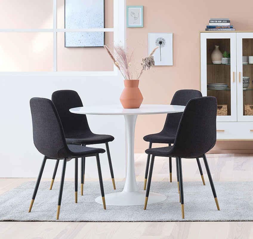 Modern dining chairs in black and gold around a white, round table 