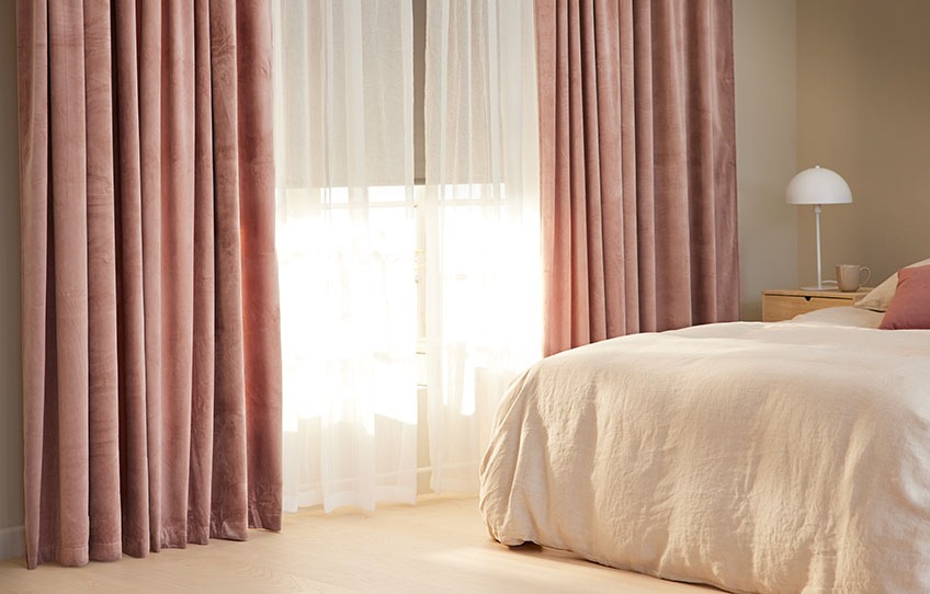 Bedroom with black out roller blinds half way up and light curtains open 