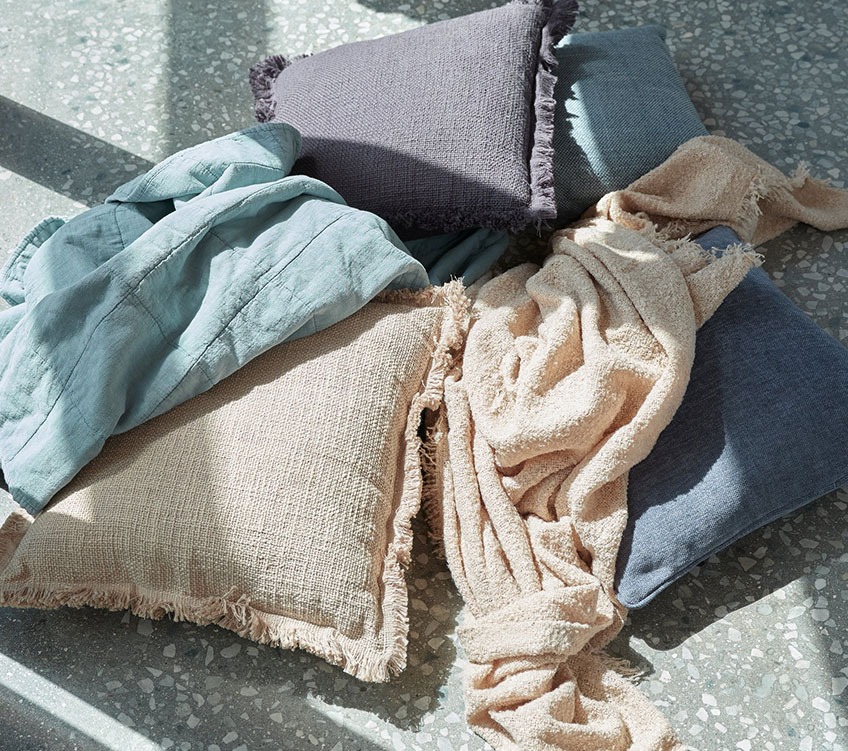 VALMUE lbue throw, ROSE beige throw, HORTENTIA and HORNFIOL cushions Blue throw, beige throw, and khaki and blue cushions on the floor