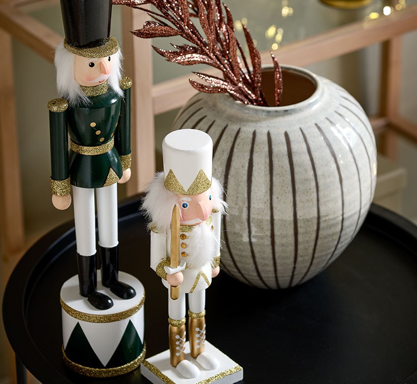 Two Christmas figurines and a vase on a black end table 