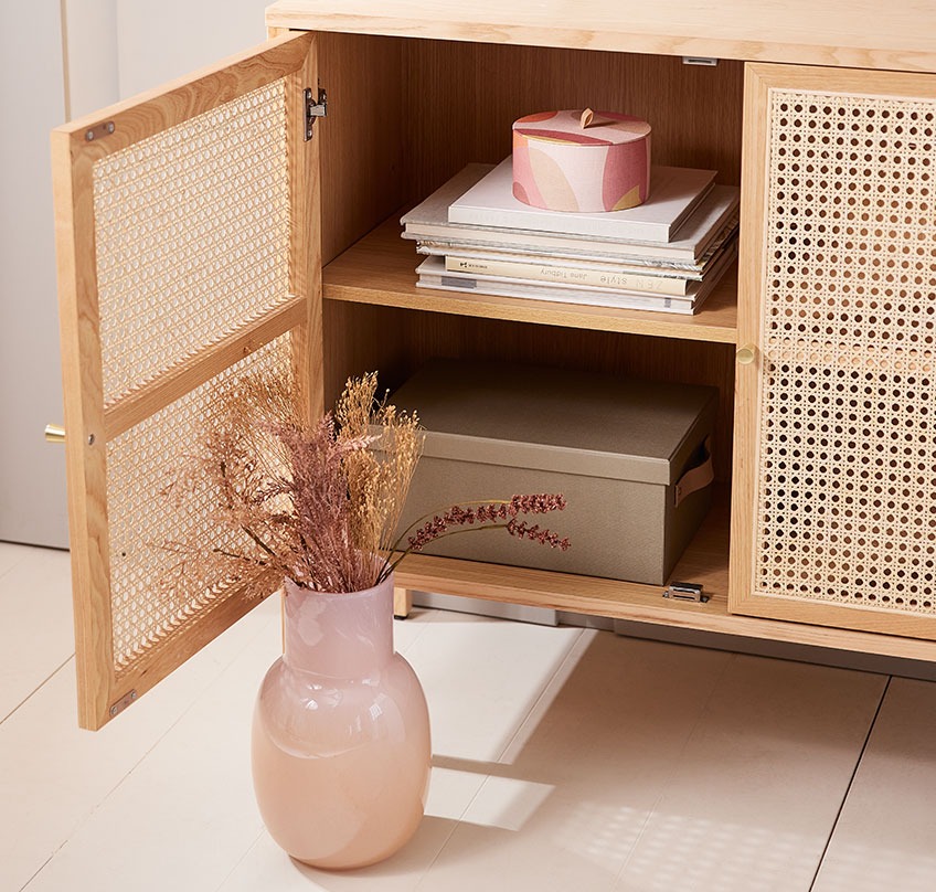 KASPER vase and round OLA storage box in HALMSTAD sideboard Mouth blown vase with a bouquet of artificial flowers in front of sideboard with an open door and a round storage box inside