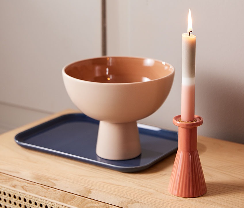 THRISTAN candlestick with IGNI candle, LEIV serving platter and CHRIS bowl Bowl on a serving platter, beside a candlestick with a striped candle