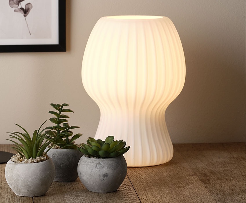 Table lamp made in fluted white glass on a wooden dining table