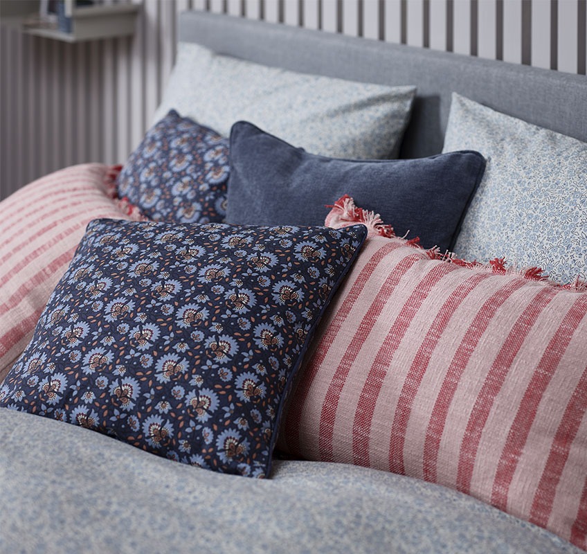Bed with decorative cushions in red and blue nuances 