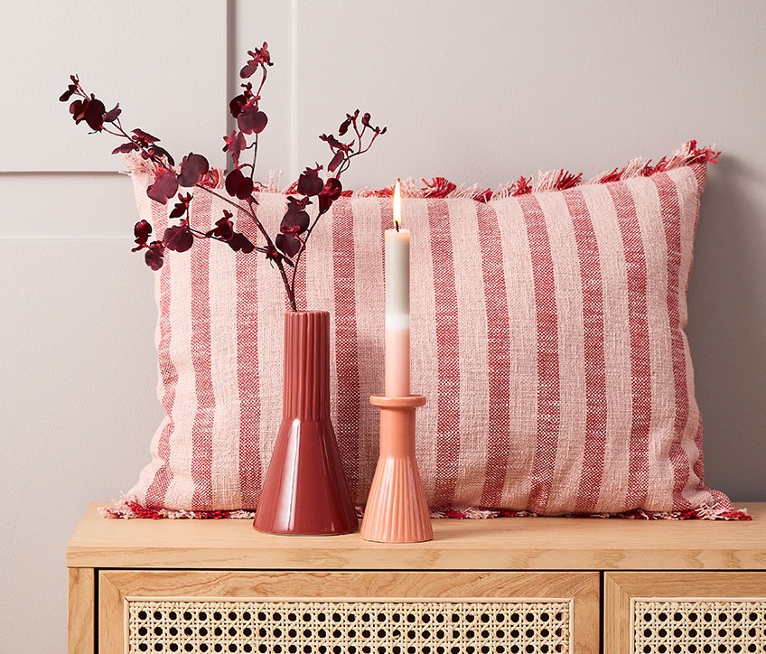 DAGFIOL cushion, RAGNAR artificial flowers, EGMUND vase and THRISTAN candlestick with IGNI candle Striped cushion behind red vase and candlestick with striped candle