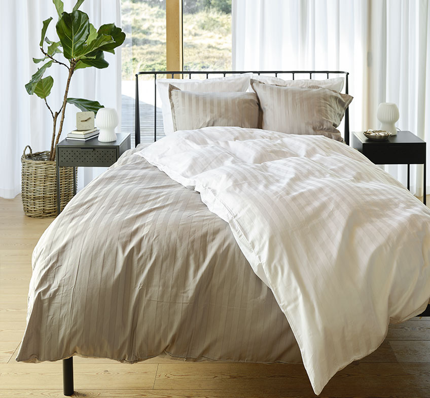 Bedroom with grey and white striped bedding on the bed and two bedside tables 