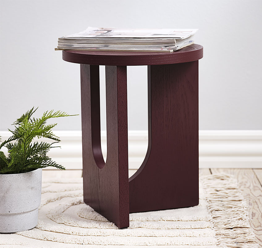 Burgundy end table with round sculptural carvings