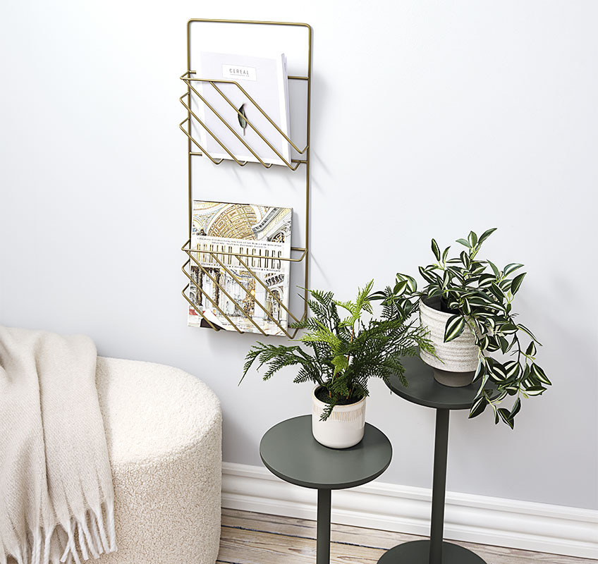 Two flower stands in green and a gold magazine holder hanging on the wall 