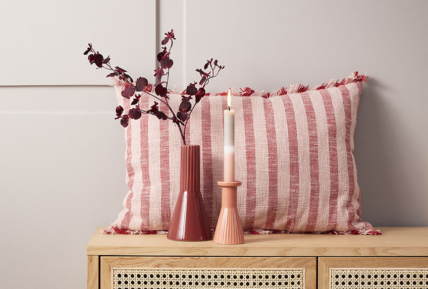 Cushion, vase and candlestick on a sideboard