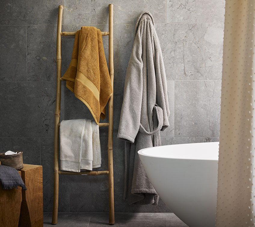 KARLSTAD and SORUNDA towels, BULLMARK bathrobe Decorative ladder with yellow and white towel and light grey bathrobe in a bathroom