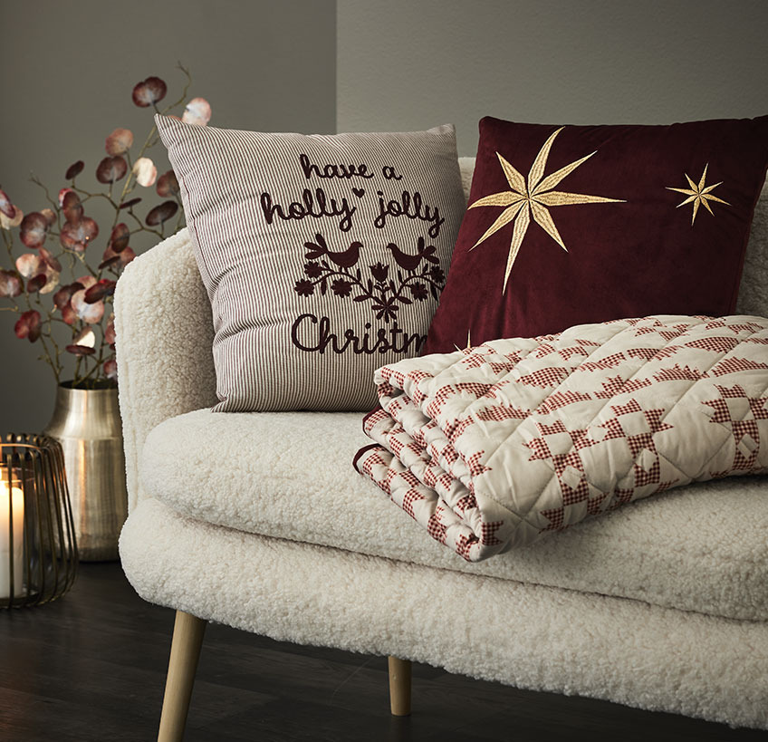 Cushions and quilted blanket with Christmas motifs in a white sofa