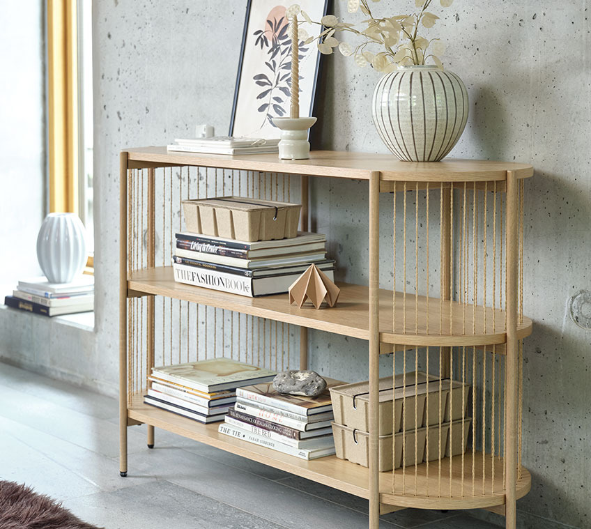 The EGELEV sideboard is also available in black Living room with a light oak sideboard with a vase on top and books and storage boxes on the shelves