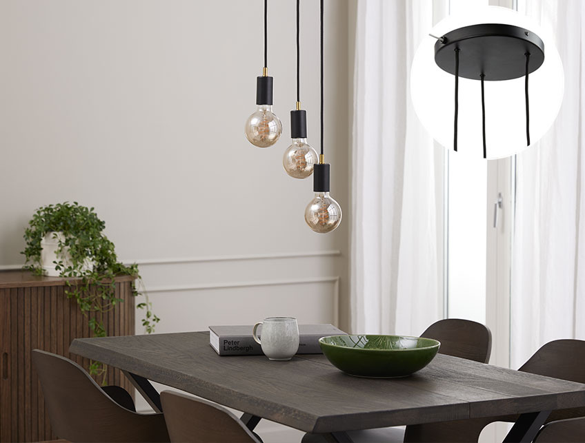 Black pendant light with large light bulbs above a dinner table 