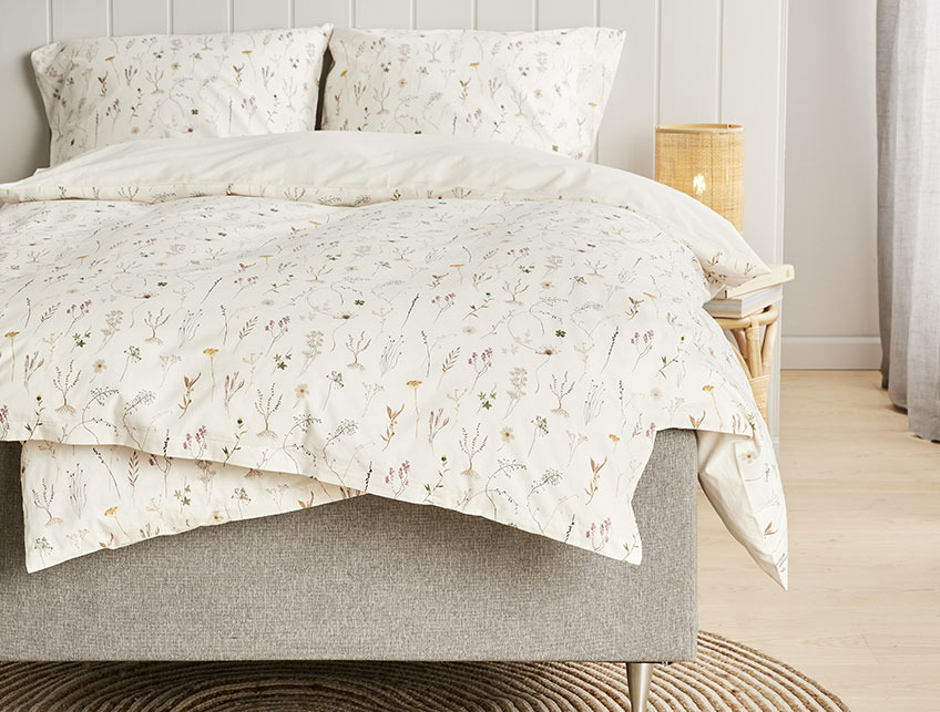 Flowery bed linen in a light bedroom 