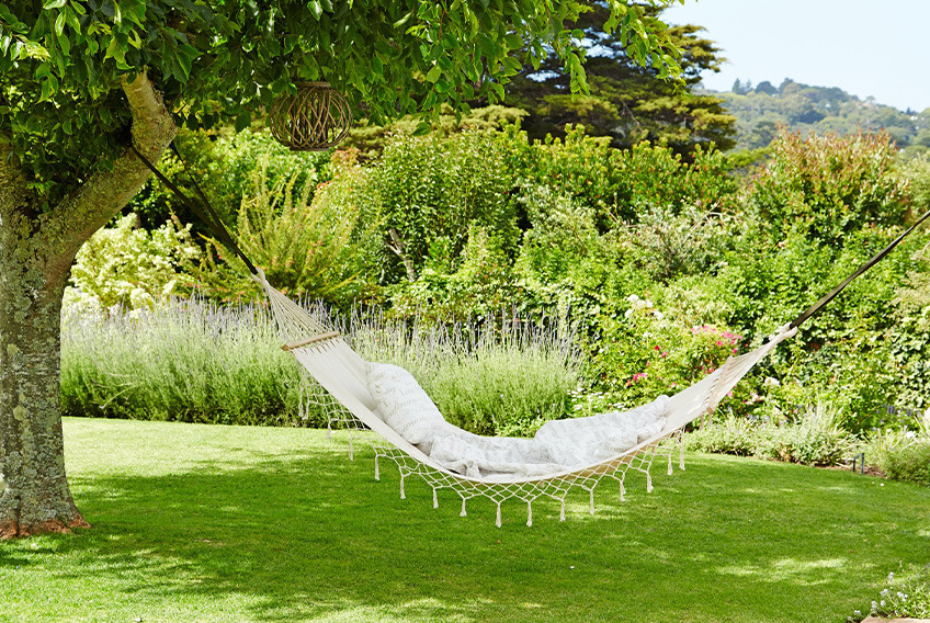 BERGFINK hammock White hammock suspended between two trees in garden