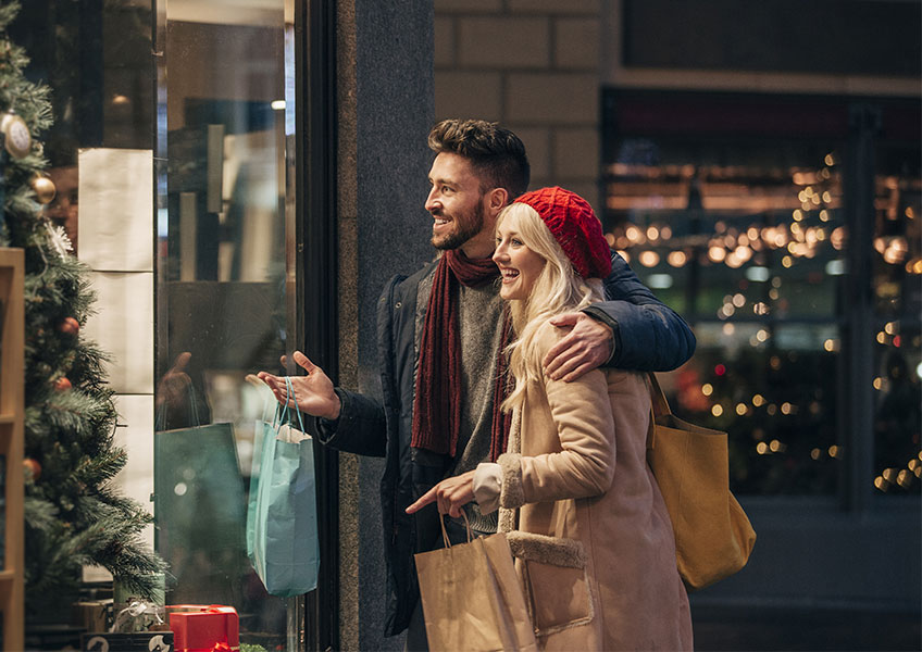 Young couple Christmas shopping and looking at a store window